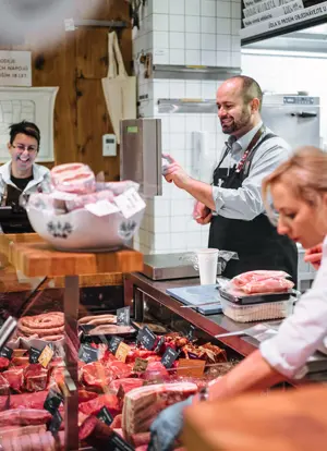 Butcher shop staff weighing meat at the counter.