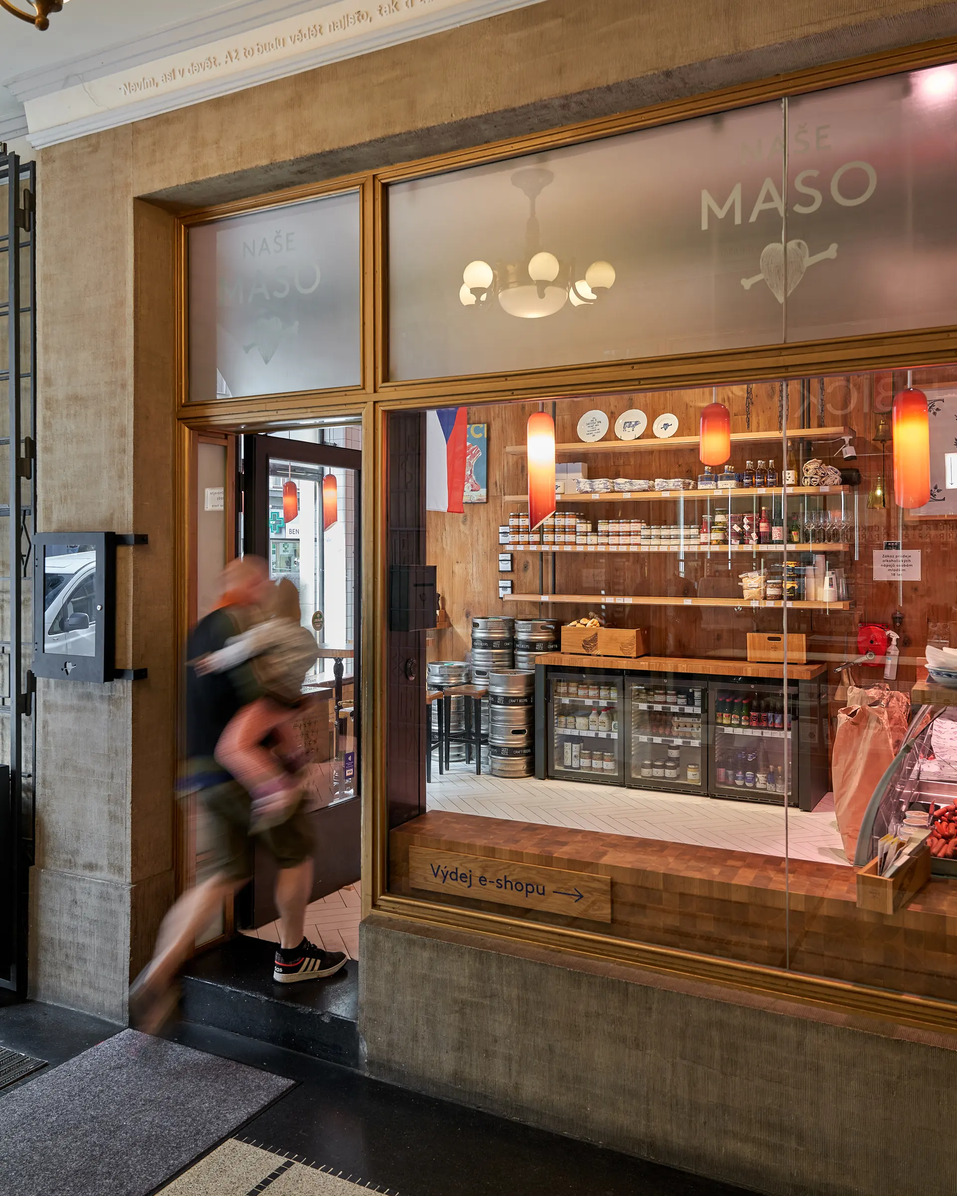 Entrance to Naše maso butcher shop with shop window and interior.