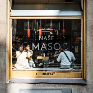 Naše maso butcher shop window on Dlouhá Street.